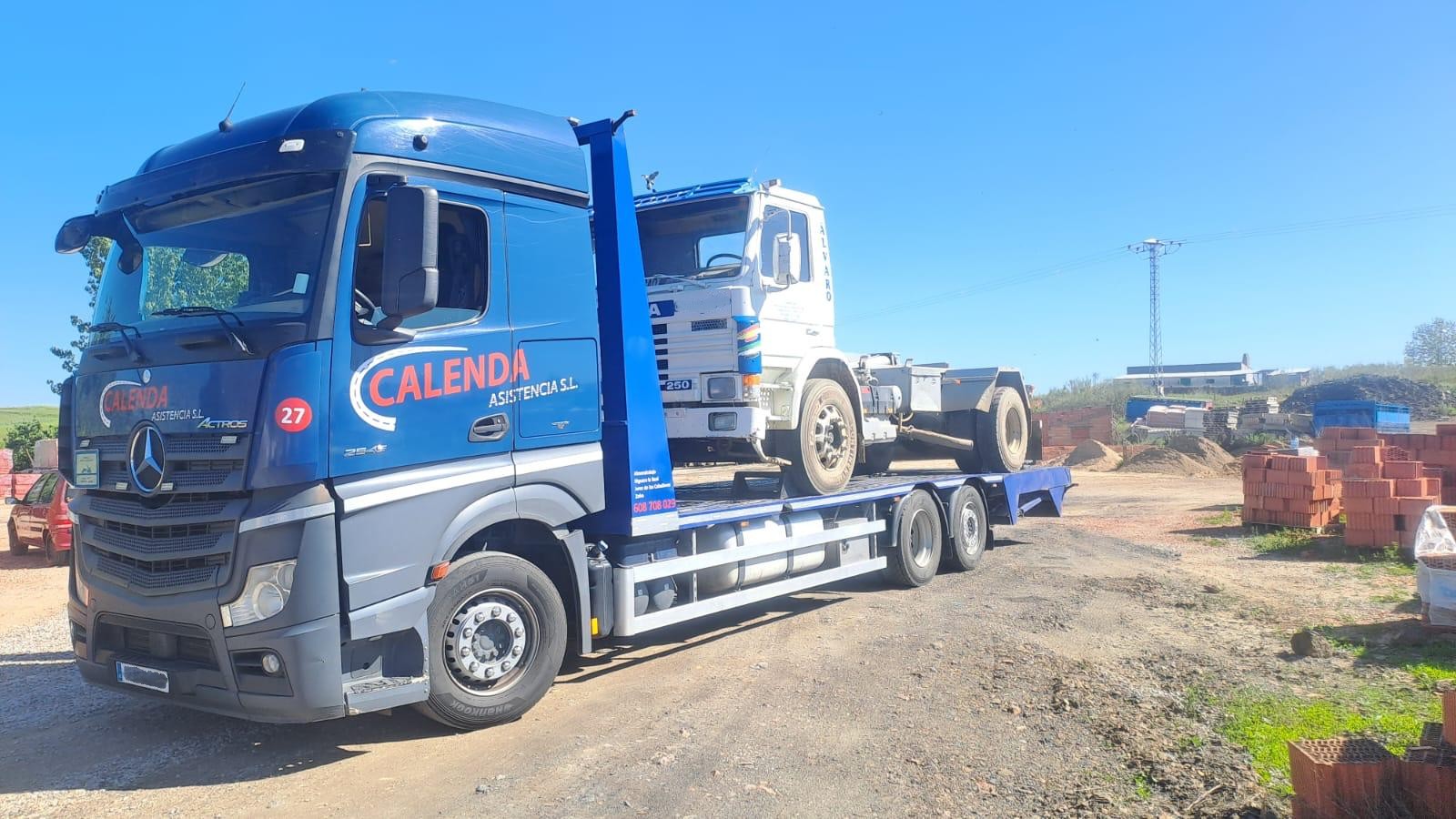 Camión azul con plataforma en entorno industrial
